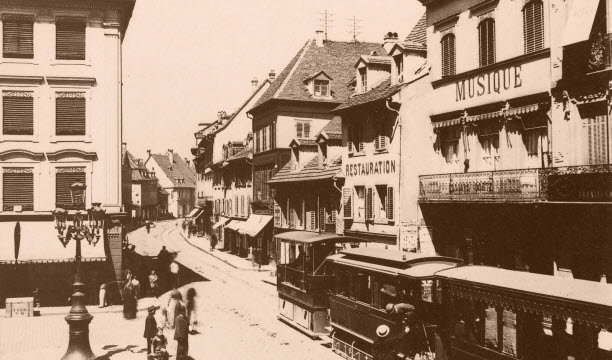 Đây là đường xe điện chạy bằng hơi nước trên rue du Sauvage, tại Place des Victoires, năm 1885. Công ty Tramways Mülhausen (TM) được thành lập vào ngày 21 tháng 6 năm 1884 mà không cần trợ cấp. Tài liệu Giao thông công cộng Mulhouse (TCM)